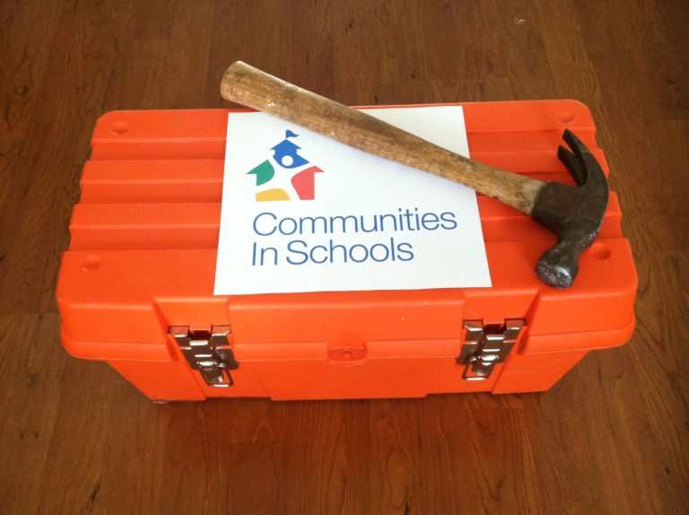 orange tool box with hammer on top and Communities In Schools logo