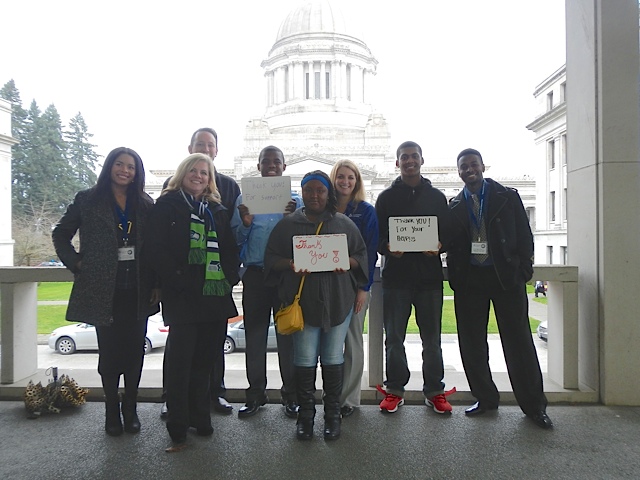 group shot of 8 students and staff with thank you signs in front of the Washington state legislative building in Olympia