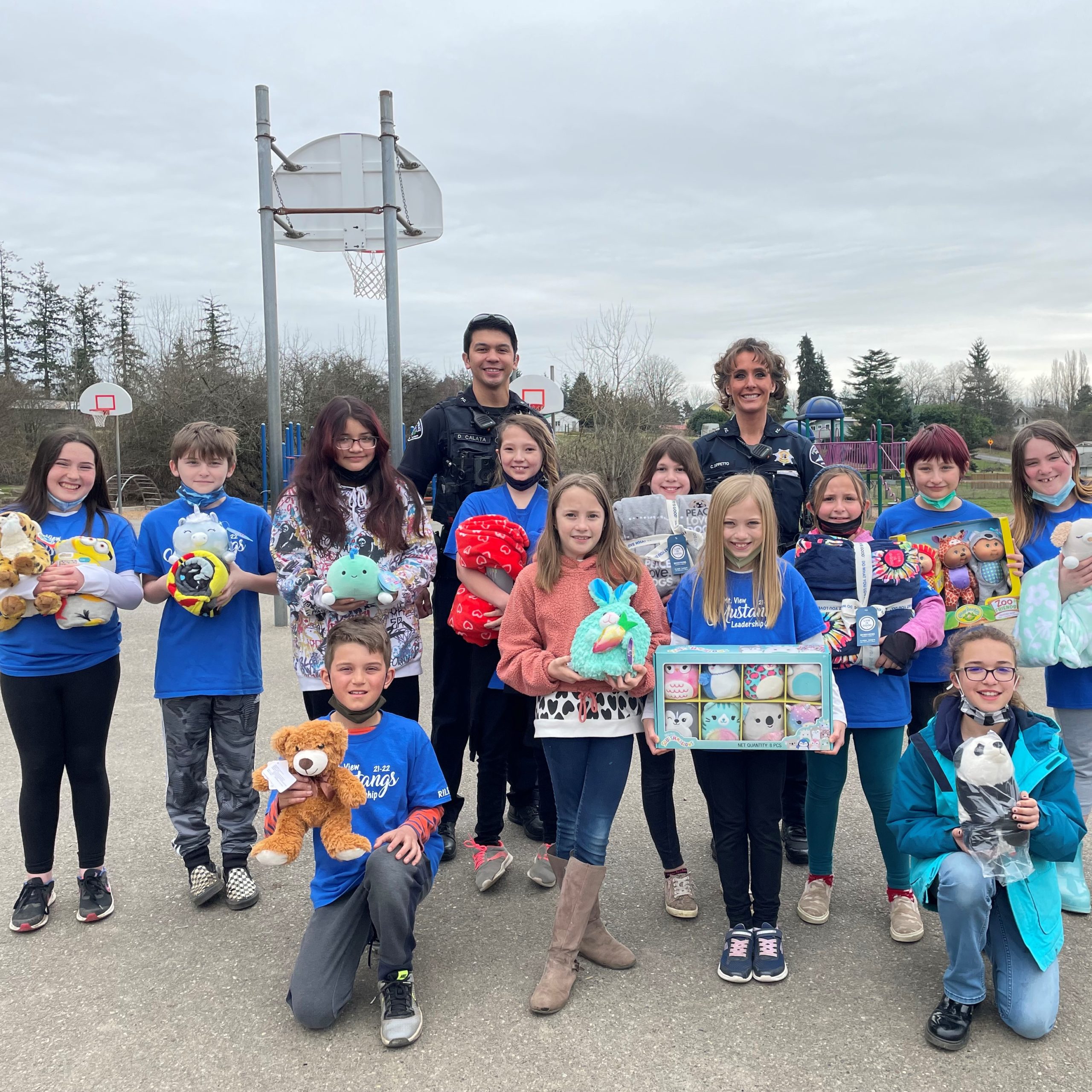 Young students holding teddy bears and other stuffed animals htey collected during a stuffed animal drive to benefit a local police department