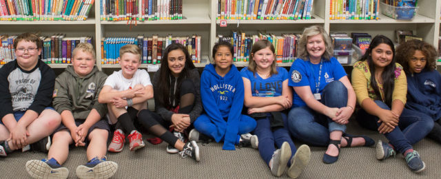 Students sitting cross-legged in the library with their site coordinator