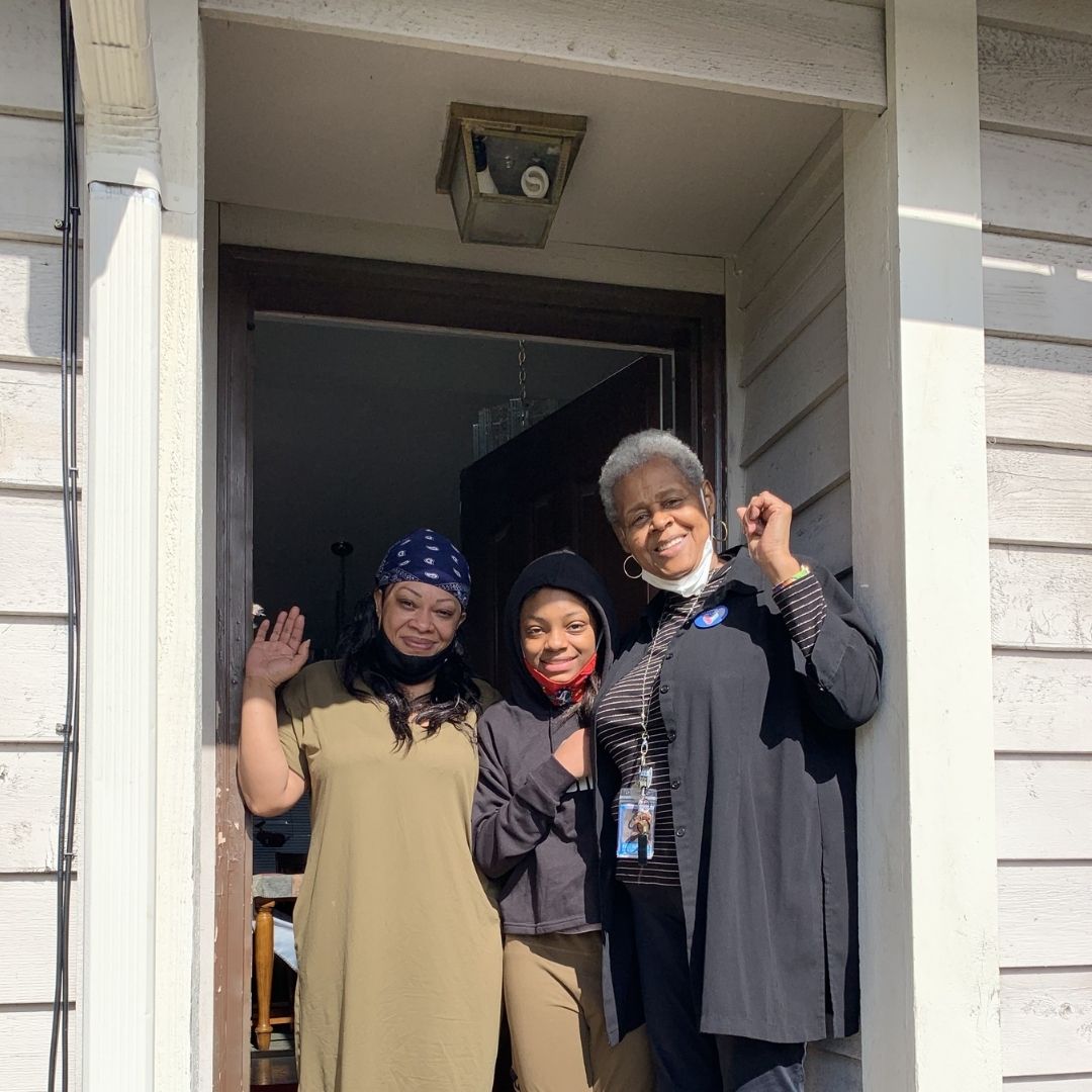 Pat with a parent and smiling student at their door front.