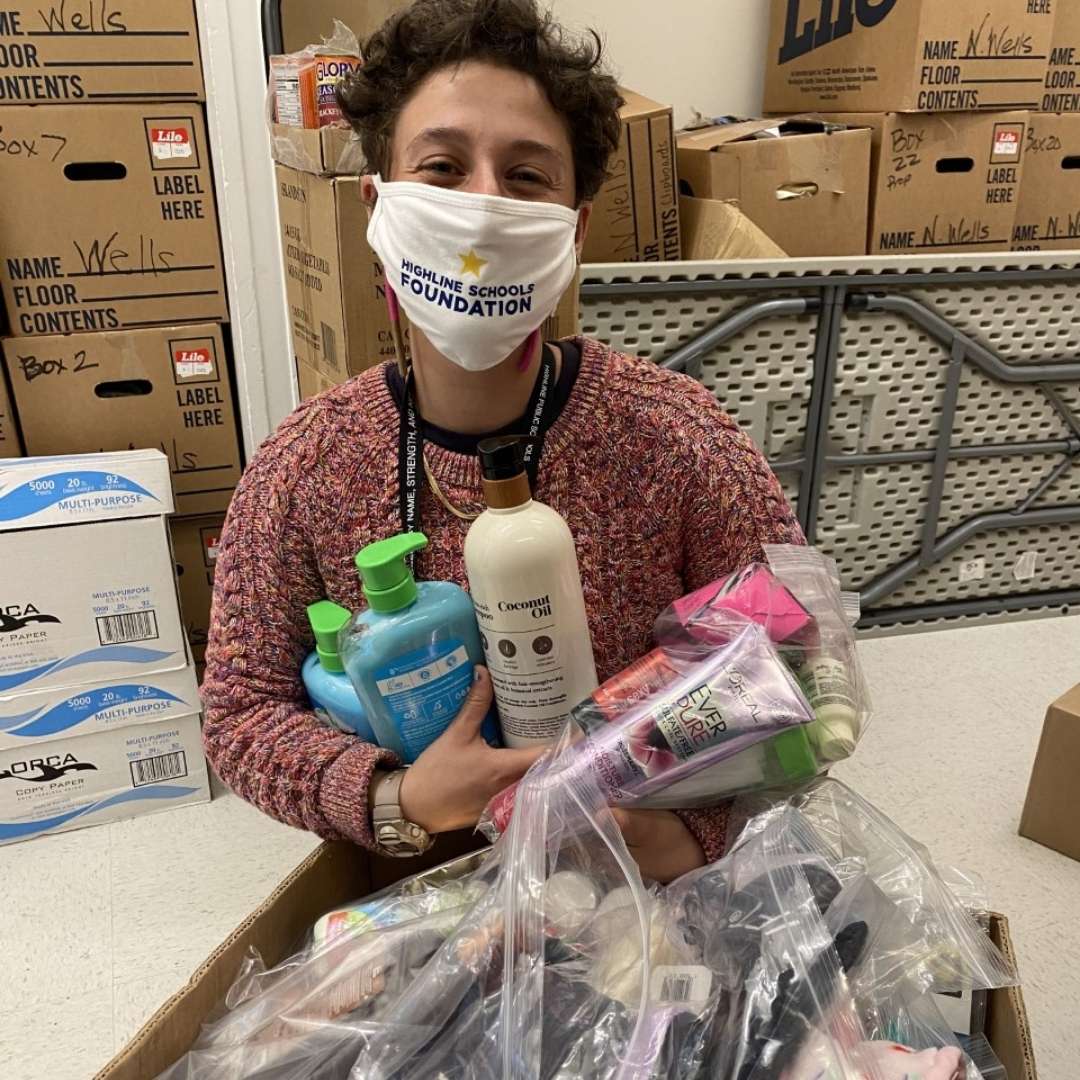 Staff member with arms full of product for families and box full of more items.